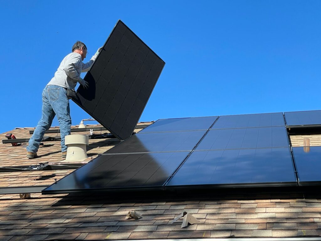 A contractor installing solar panels on the roof of a home