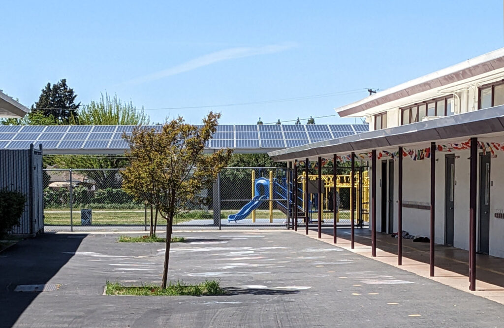 The courtyard of a public school with a playground in the background.