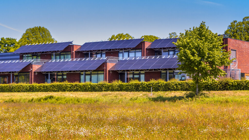 A public school with solar panels on the roof next to a field